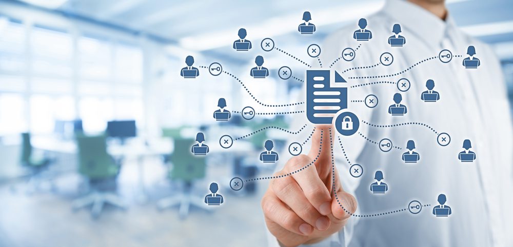 A person in business attire touches a virtual screen displaying connected icons of people and documents, symbolizing electronic document management and network security in a small business office environment.